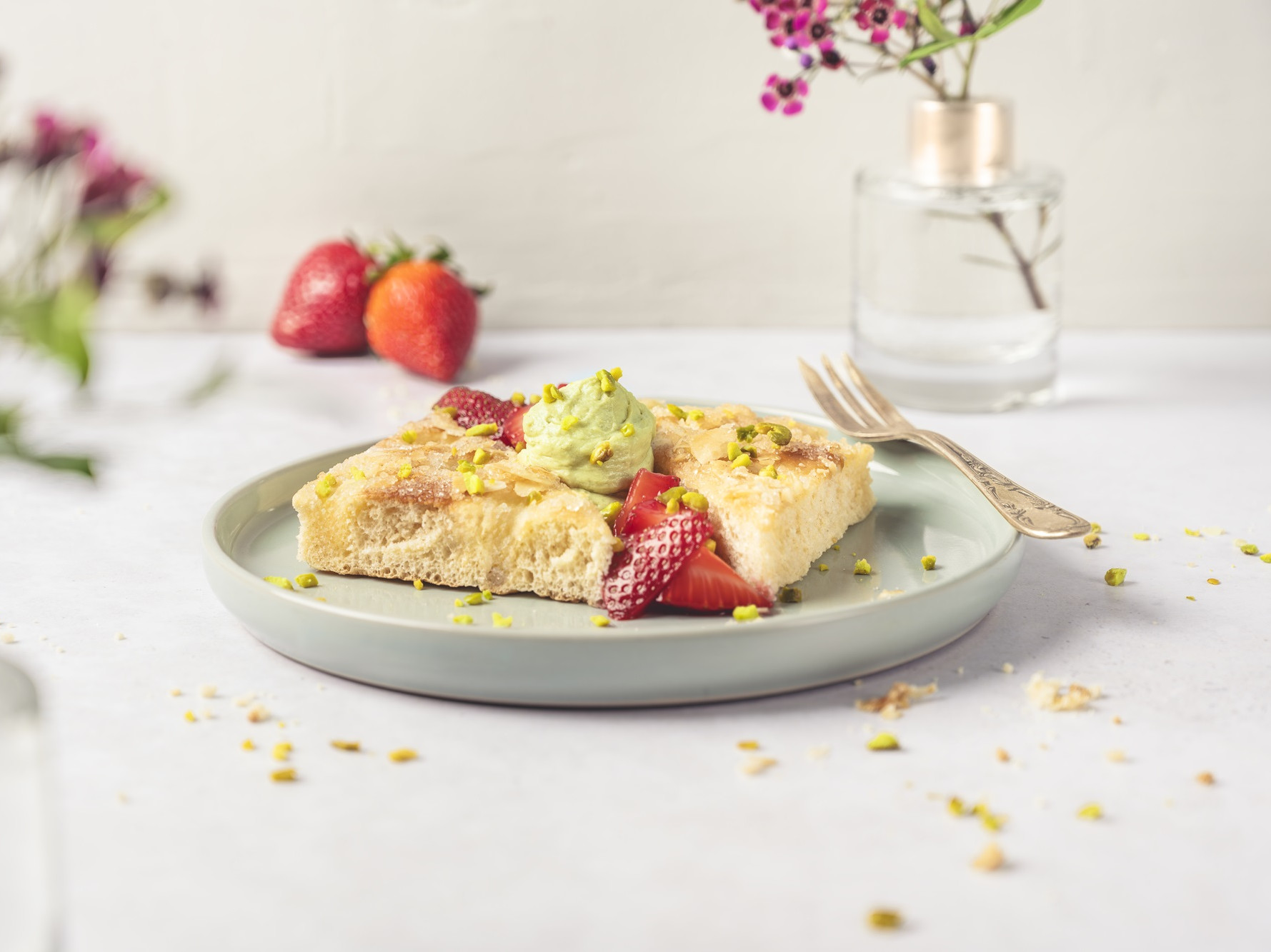 Butterkuchen auf einem Teller mit Erdbeeren und Pistaziensahne